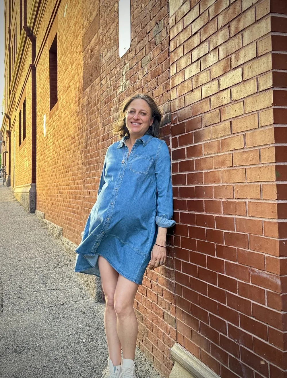Jess Barzell, pregnant at 49, leaning against a brick wall