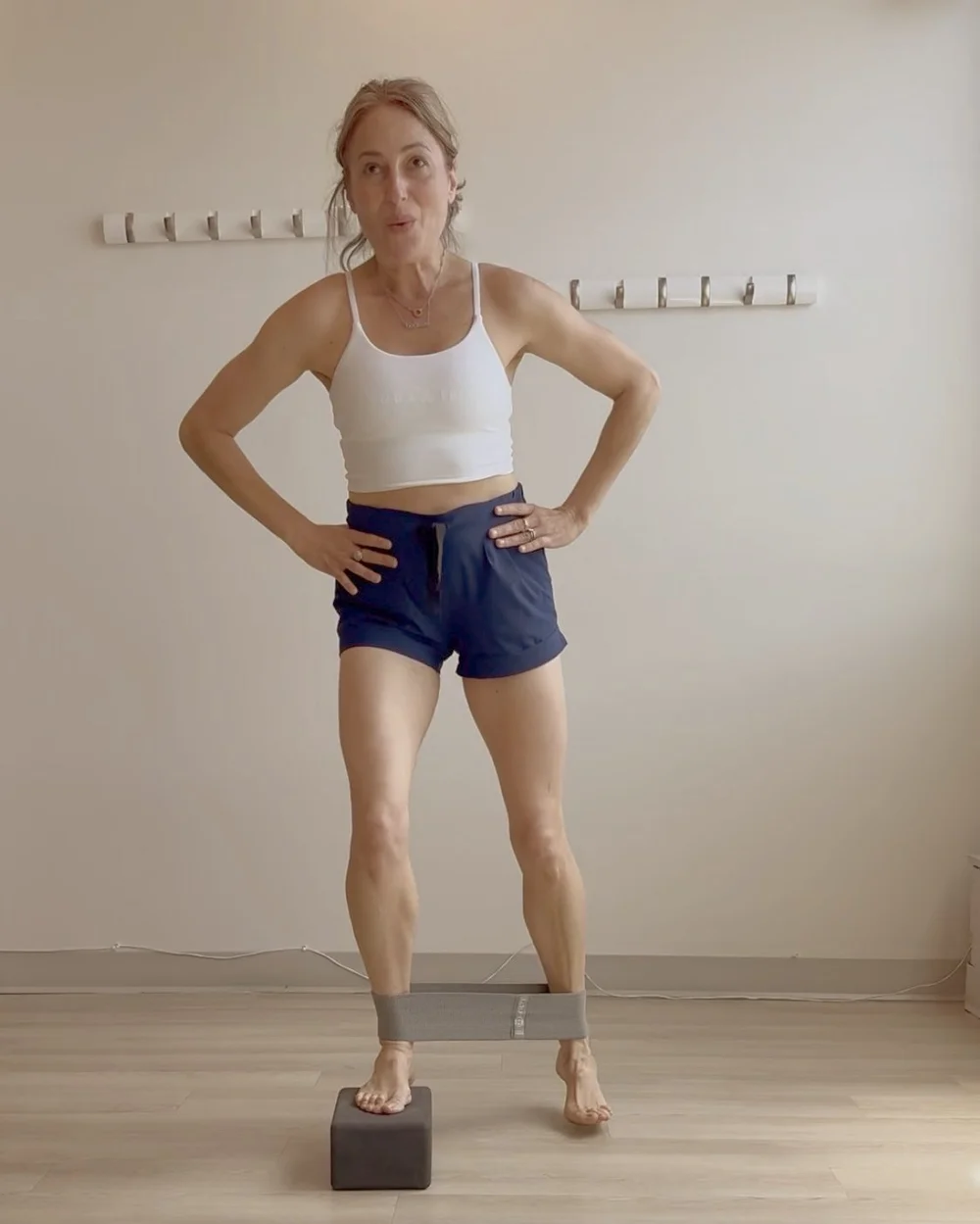 Jess demonstrating a banded balance exercise on a yoga block