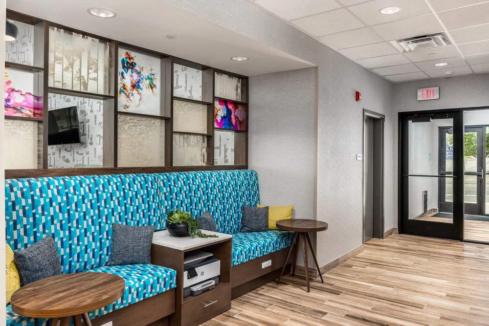 Blue patterned banquette seating beneath a grid of framed artwork in the hotel lounge.