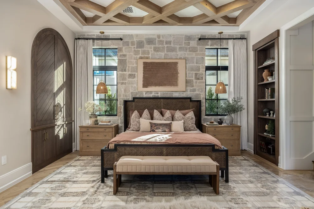 Bedroom with stone accent wall, exposed ceiling beams and arched wood door