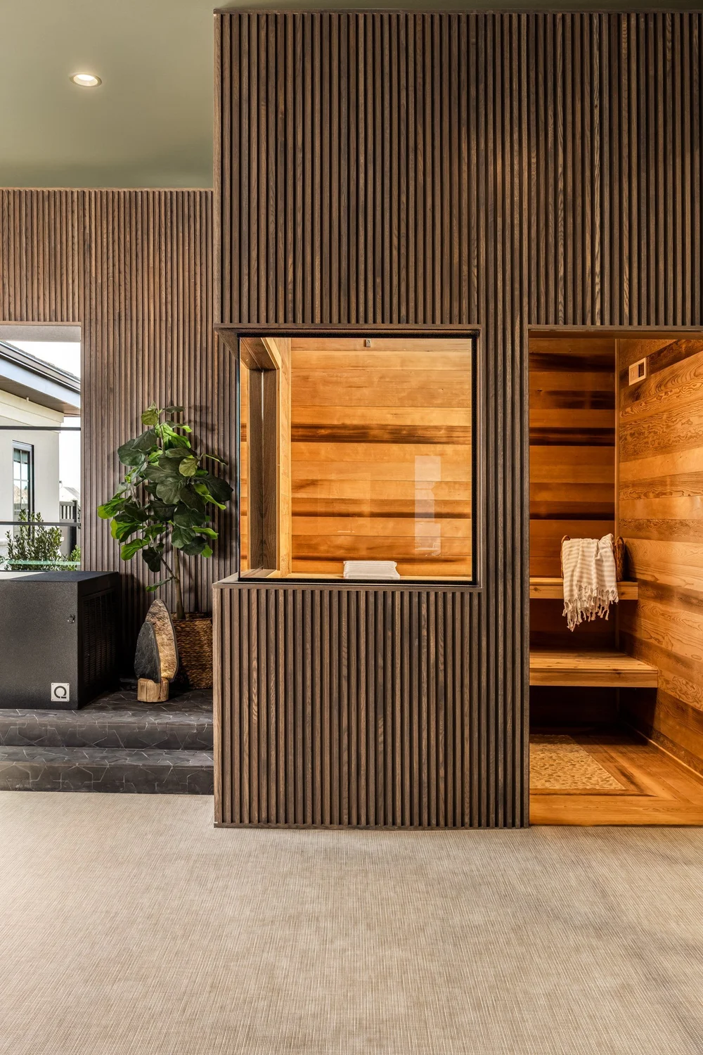 Wood-lined sauna beside a dark freestanding bathtub