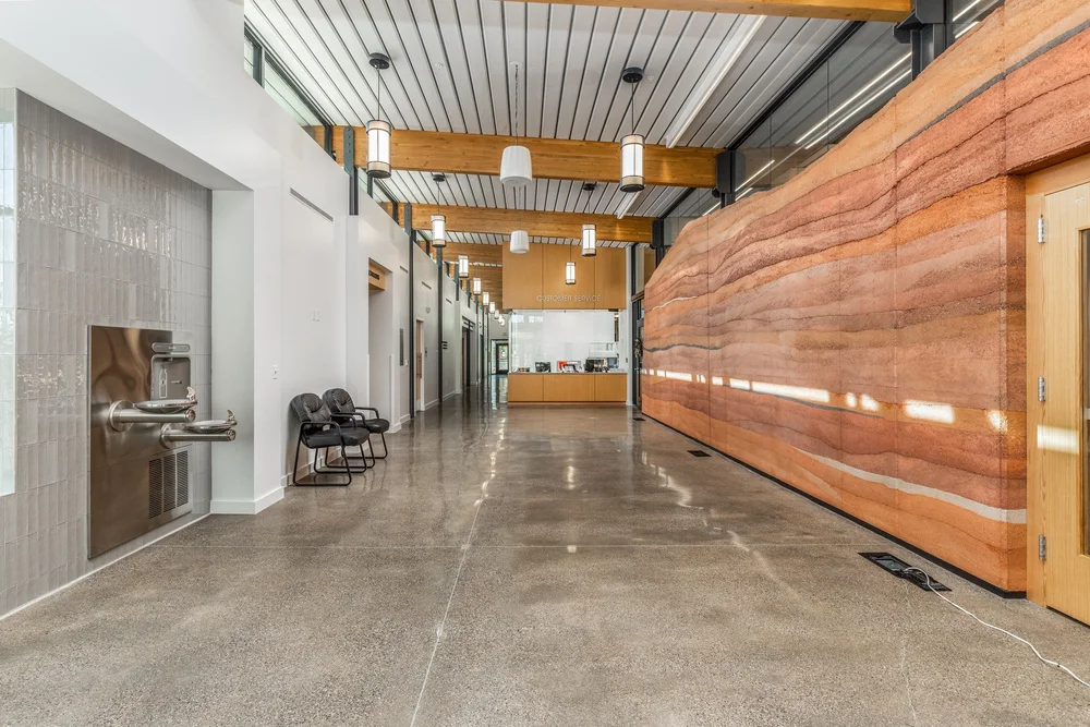 Civic building corridor with warm wood wall panels and exposed ceiling structure.