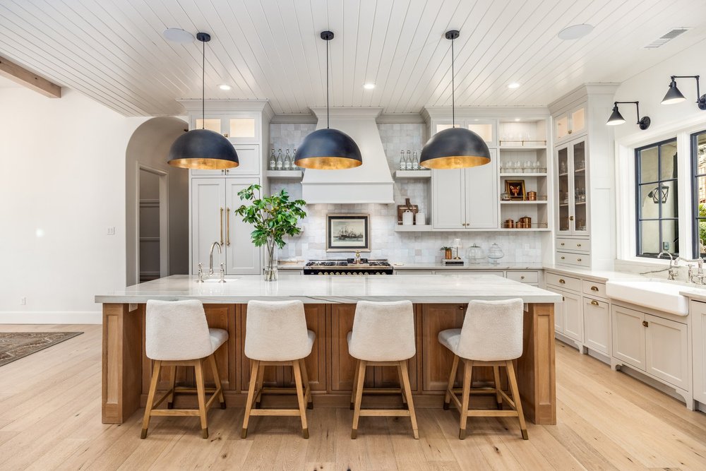 Straight-on kitchen view with a wood island and black pendant lights