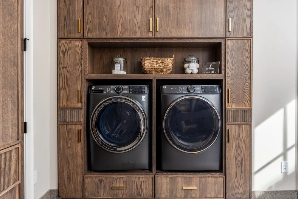 Side-by-side laundry appliances fitted into wood cabinetry