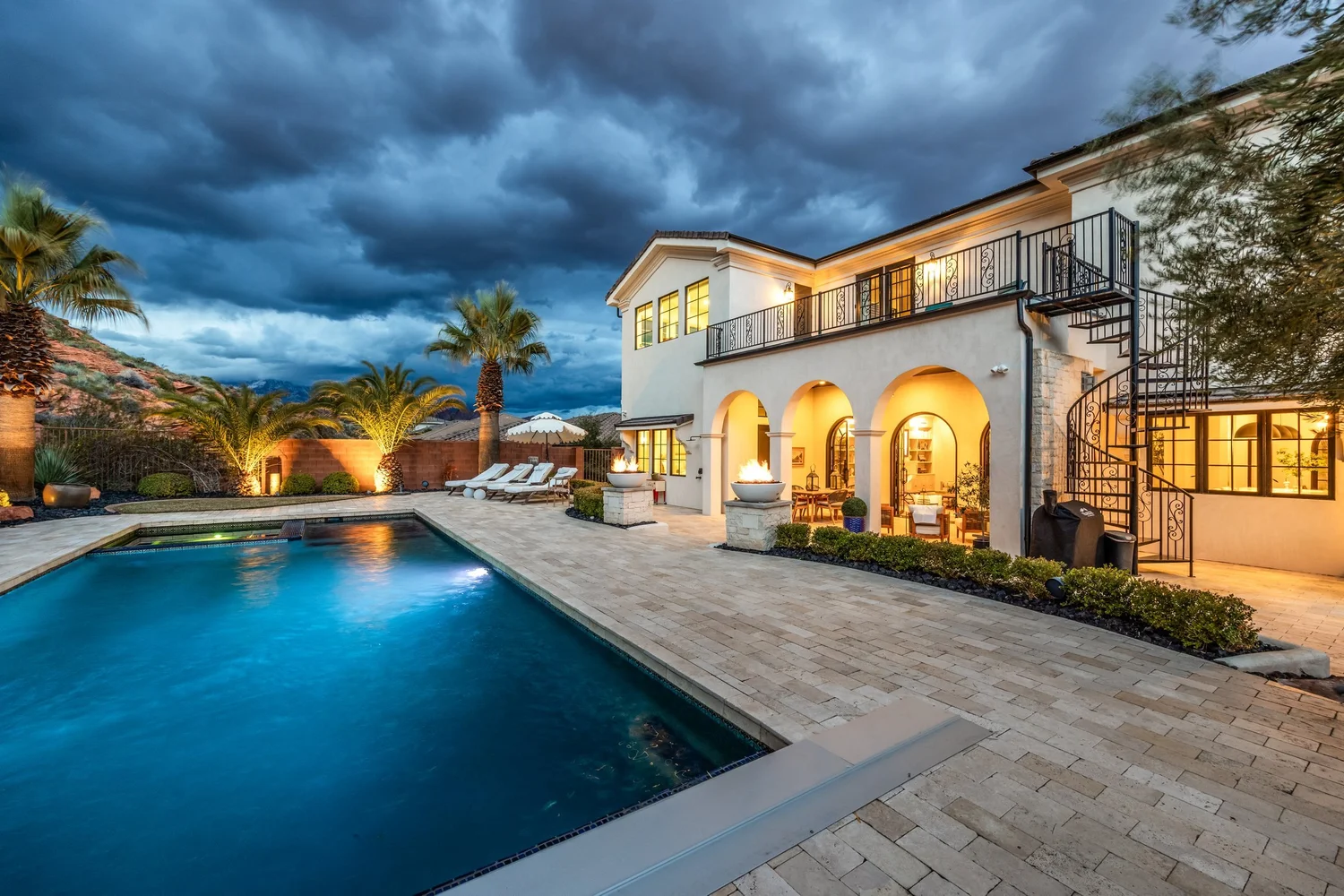 Illuminated Sunset property and swimming pool beneath a dramatic evening sky