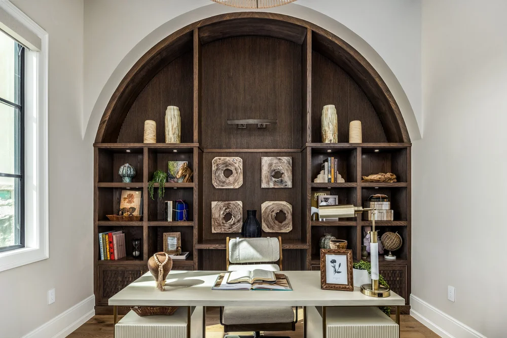 Home office with arched built-in shelving and a glass-topped desk