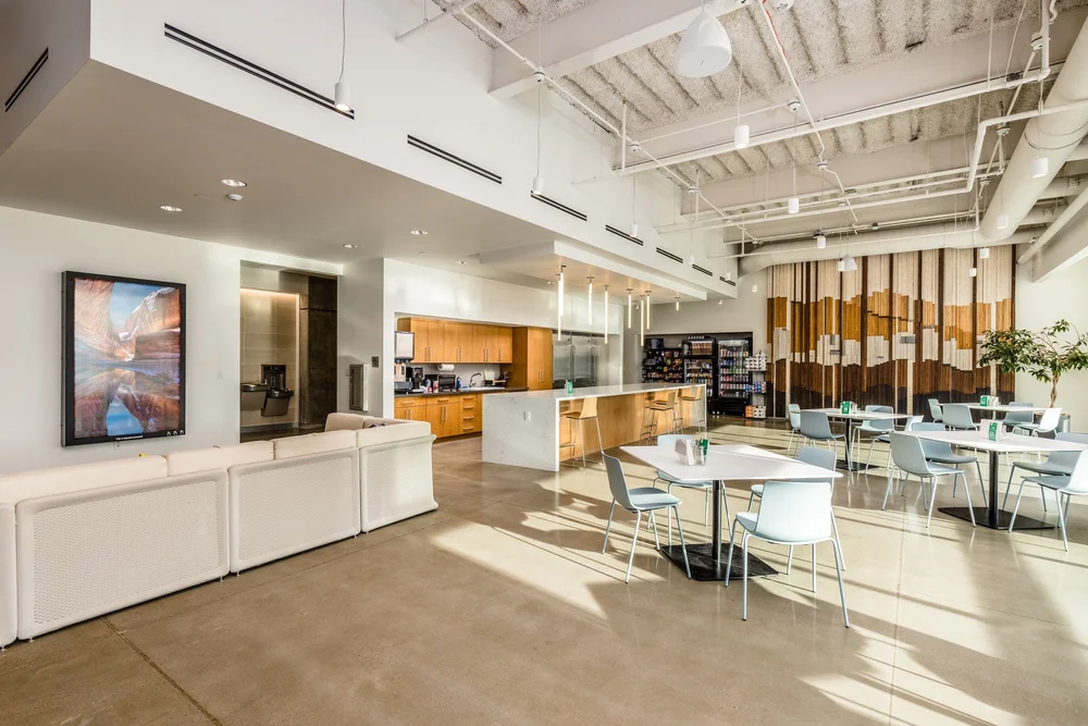 Bright employee kitchen and dining area with exposed ceiling structure.