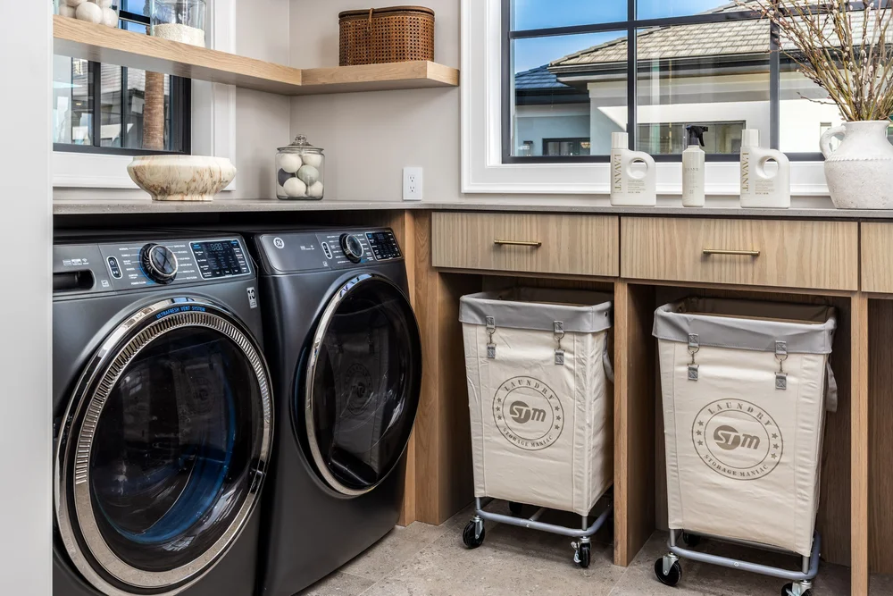 GE washer and dryer beside wood cabinetry and laundry baskets