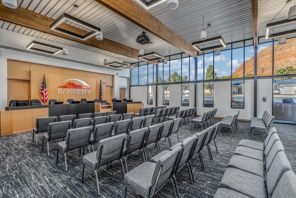 Ivins City Council chamber with rows of seating and tall windows.