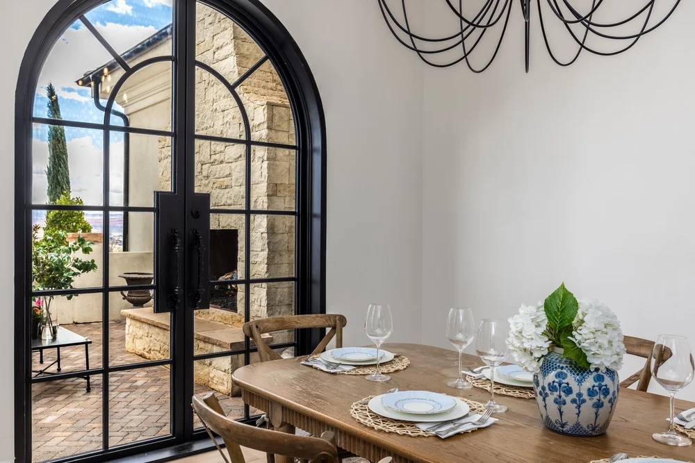 Dining area beside arched glass doors overlooking the garden