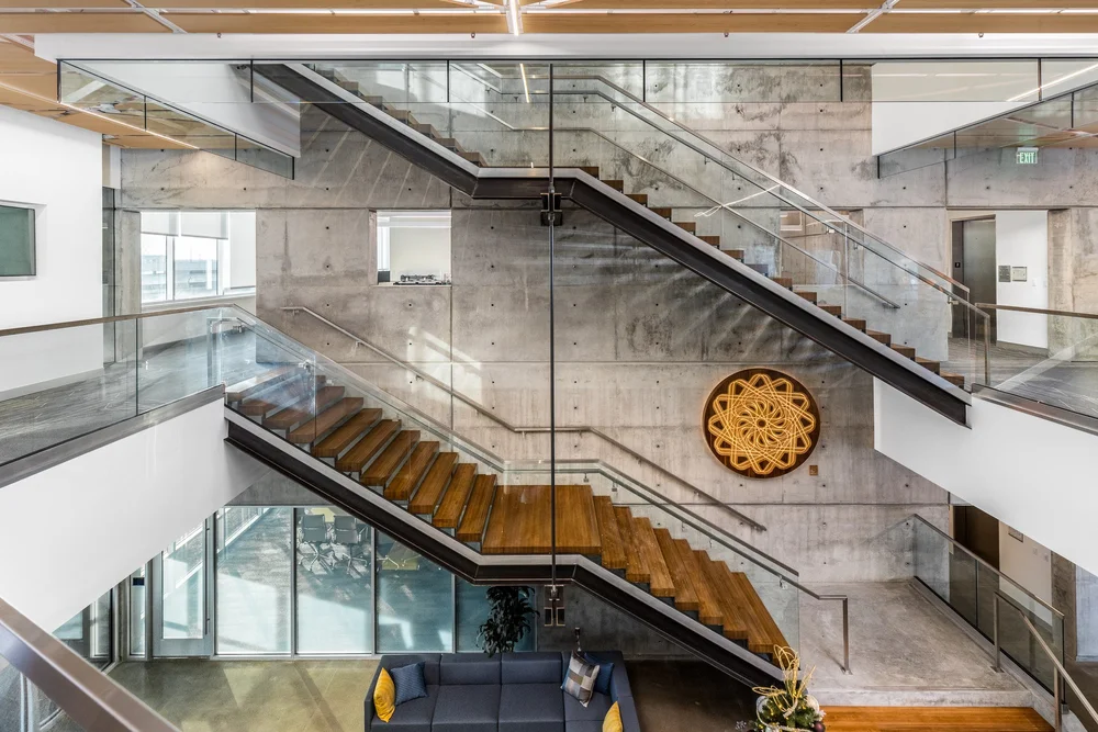 Sculptural open stairways and a decorative wood medallion against concrete walls.