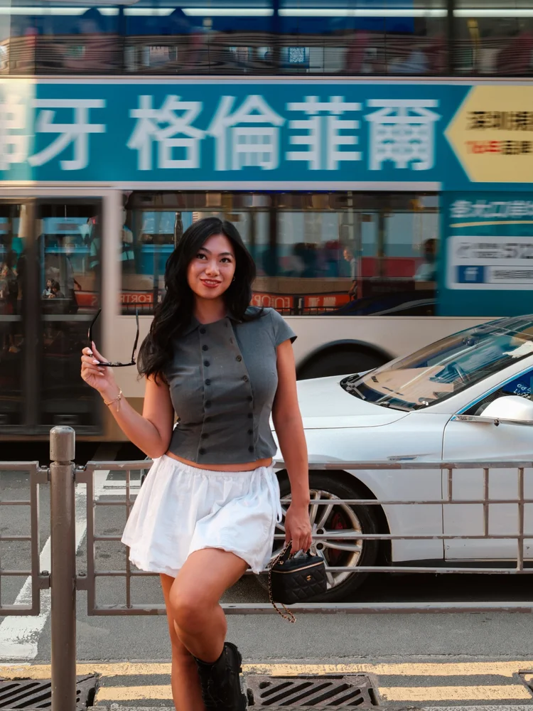 Fiona Chen on a Hong Kong street with a double-decker bus passing