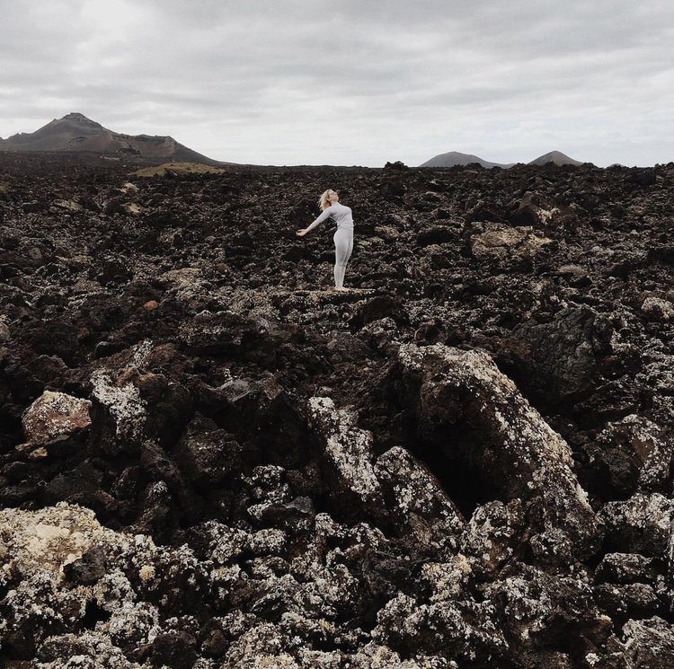 Oceana demonstrates a standing backbend within a lava field