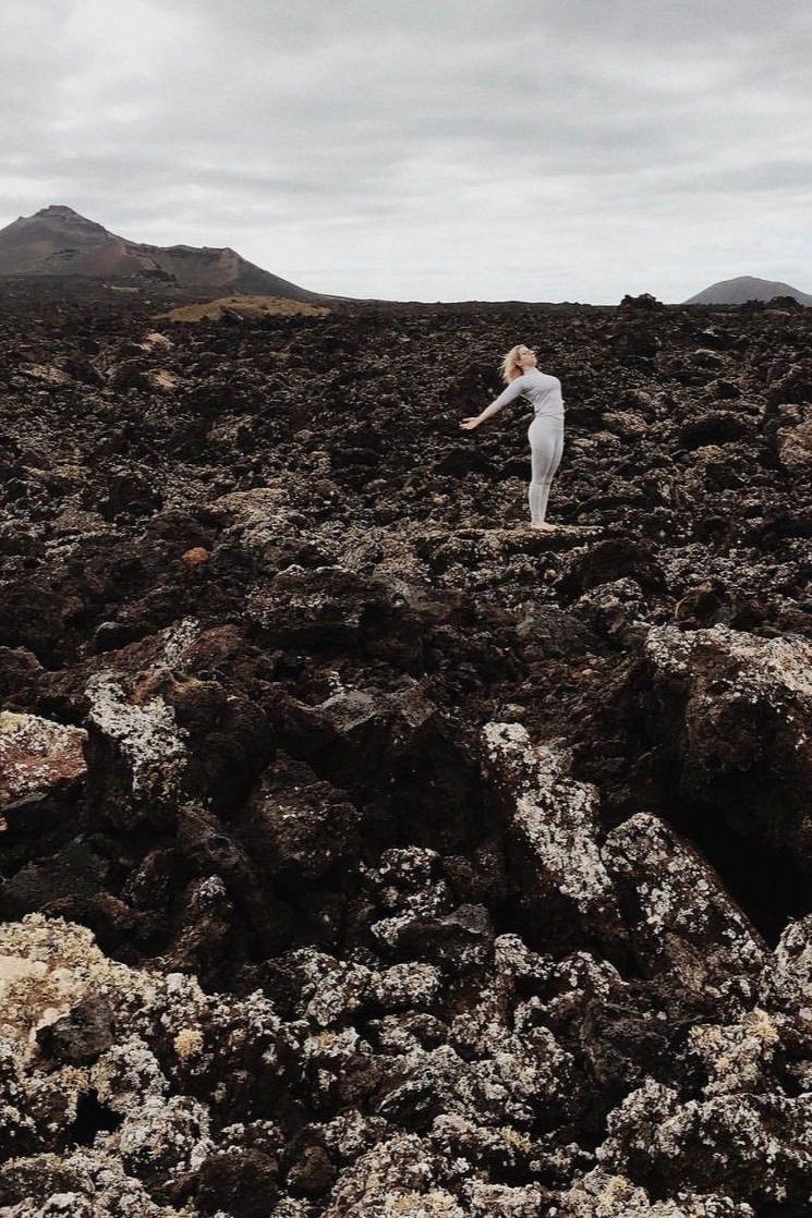 Oceana demonstrates a standing backbend within a lava field