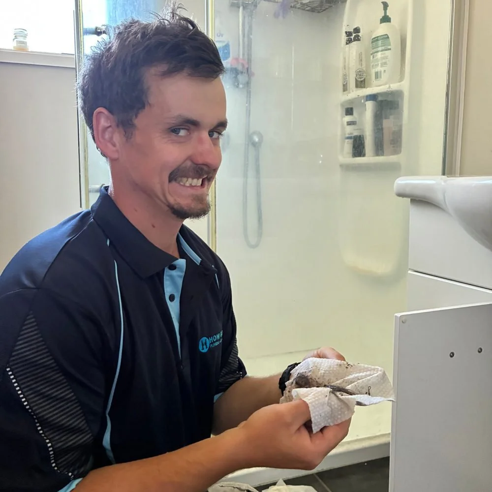Isaac holding a clump of hair pulled from a bathroom drain, grinning