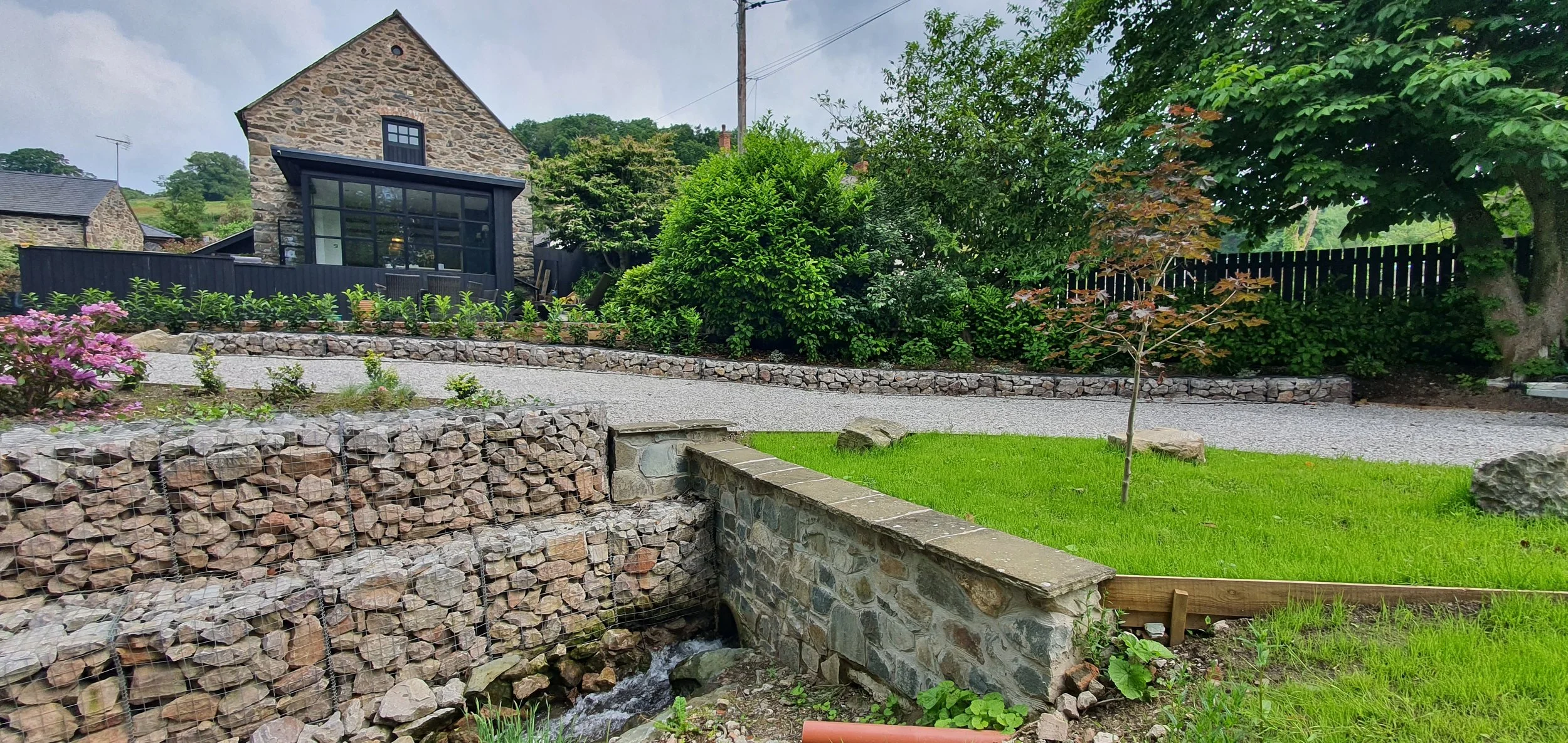 Driveway design over culverted stream in North Wales garden with retaining structure