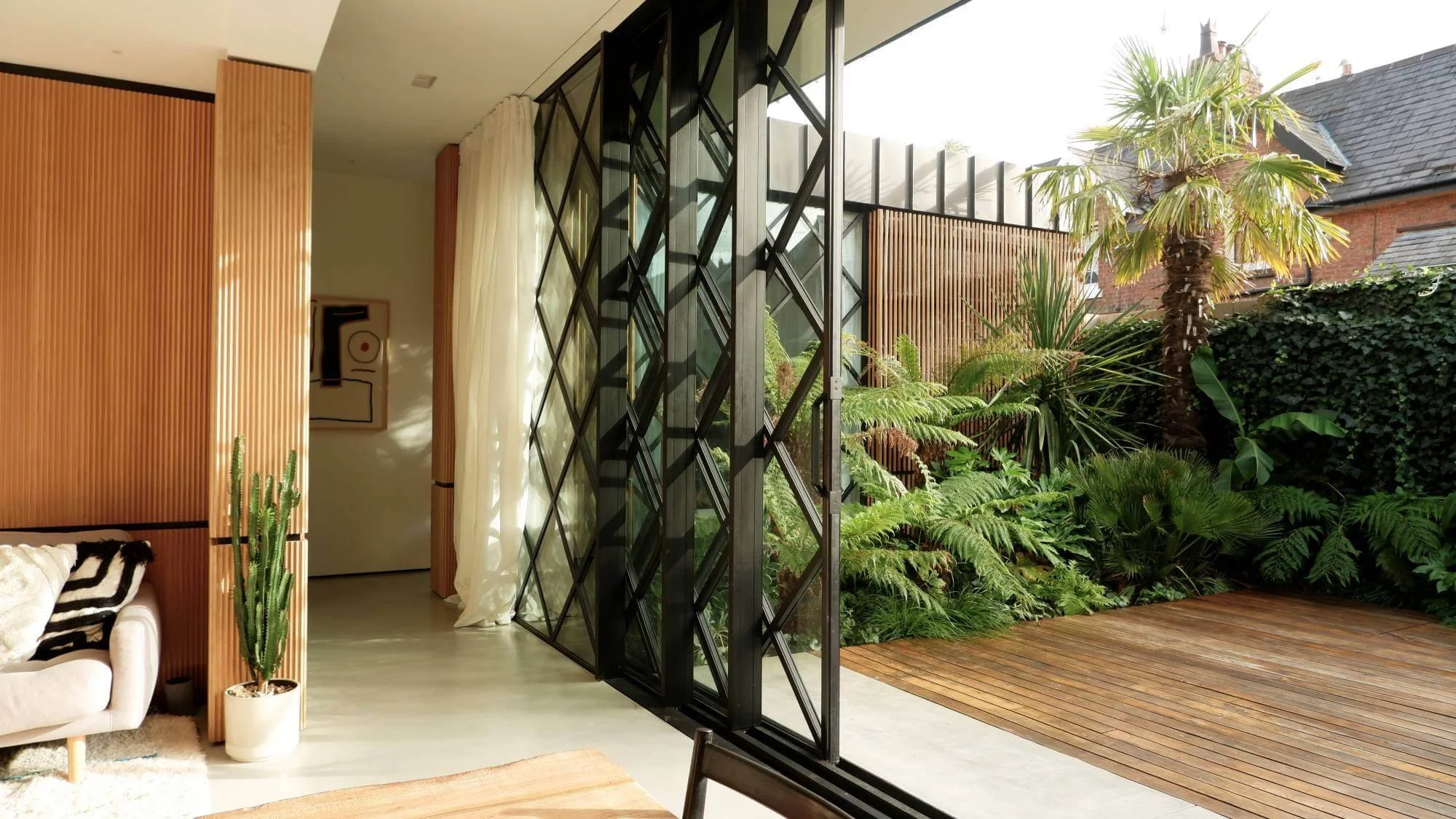 Contemporary architectural garden in Cheshire with oak decking and oak panel screens with lush exotic green structured planting