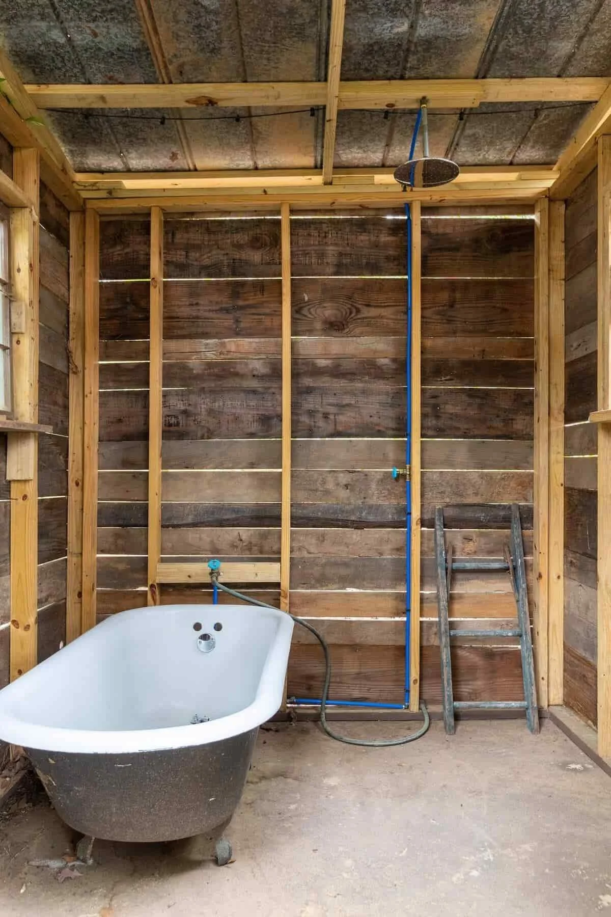 Outdoor rain shower and clawfoot tub in a rustic wood enclosure