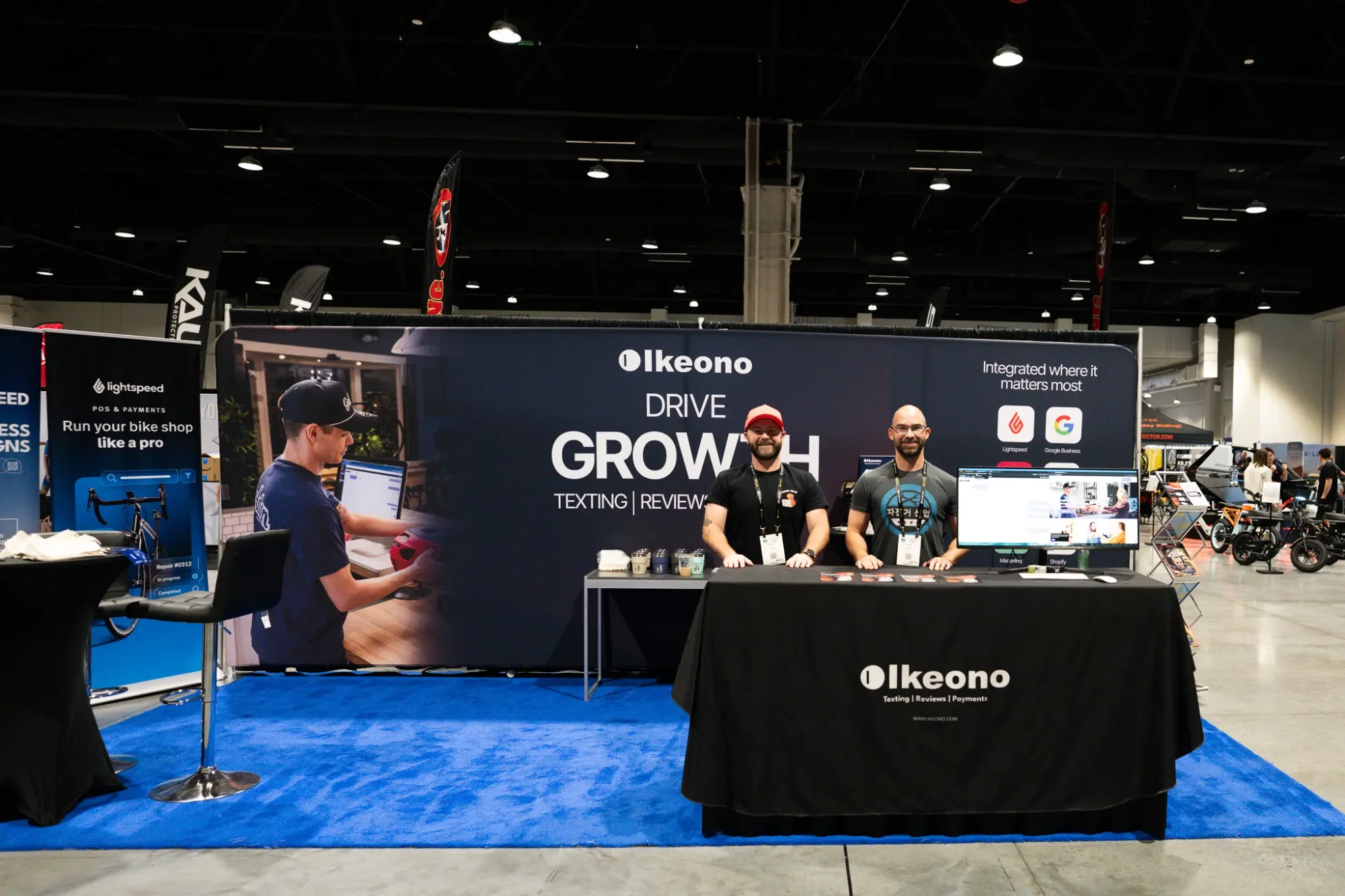 Two Ikeono team members smiling at the Ikeono booth at a bike industry trade show