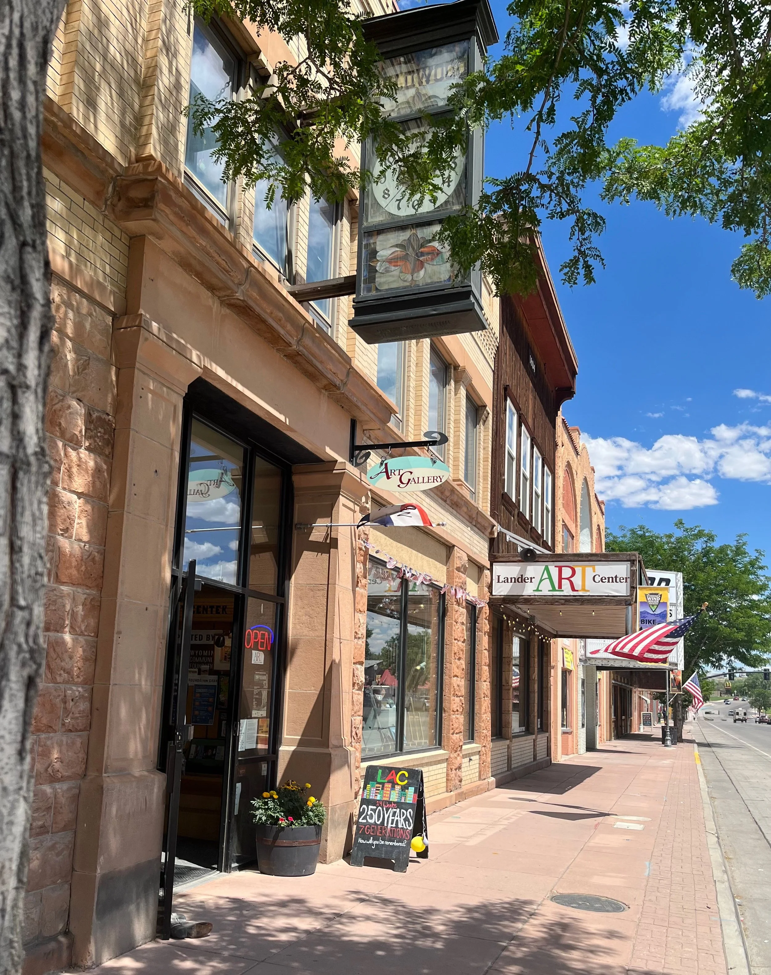 The Lander Art Center storefront on Main Street, a sandstone building with an Art Gallery sign, a lit OPEN sign, and a Lander Art Center banner over the awning.