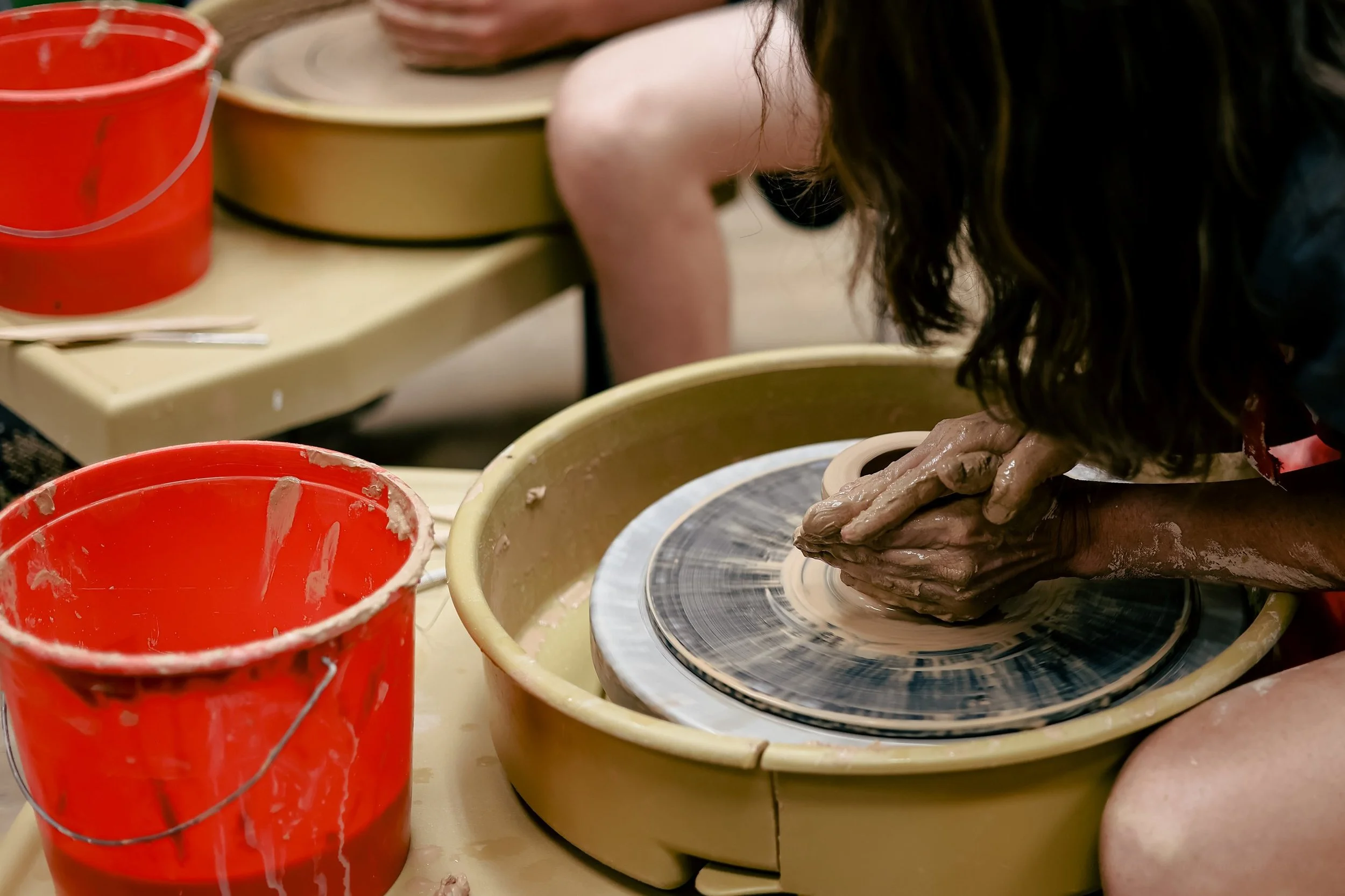 Close-up of hands shaping wet clay on a spinning pottery wheel