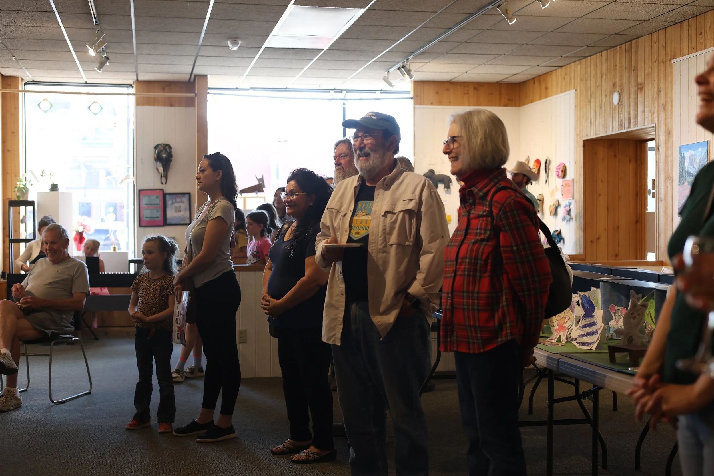 Visitors standing together in the LAC gallery during an event, artwork on the walls behind them