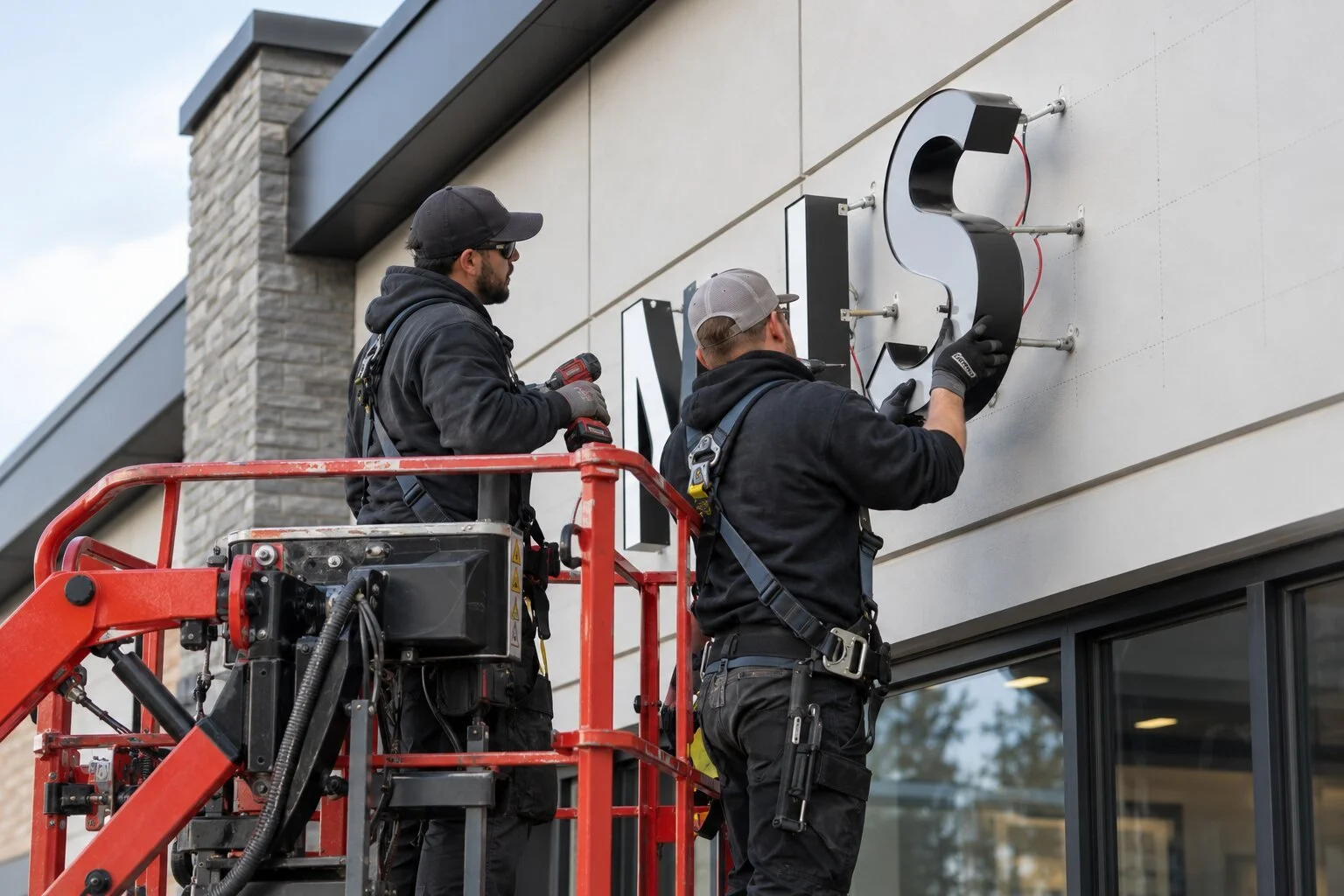 Professional installers mounting individual channel letters on a commercial facade