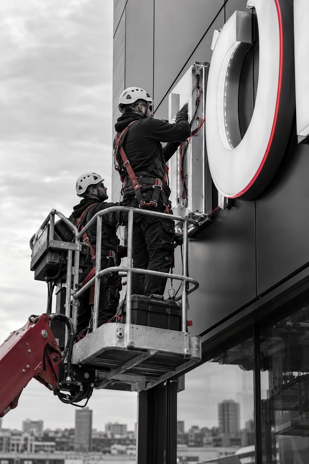 Professional technicians installing and wiring illuminated commercial signage on a building facade