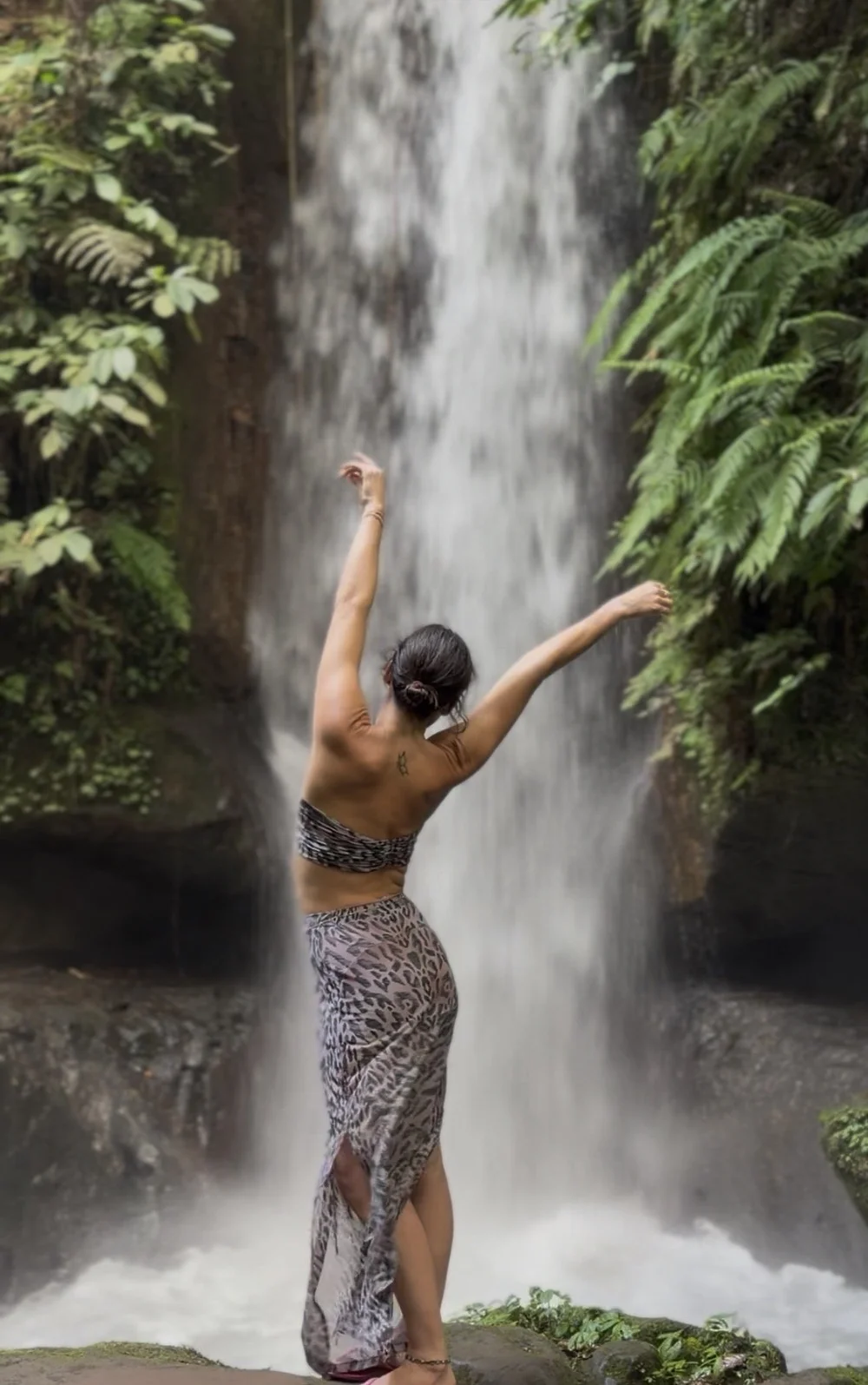 Laura bras levés face à la cascade
