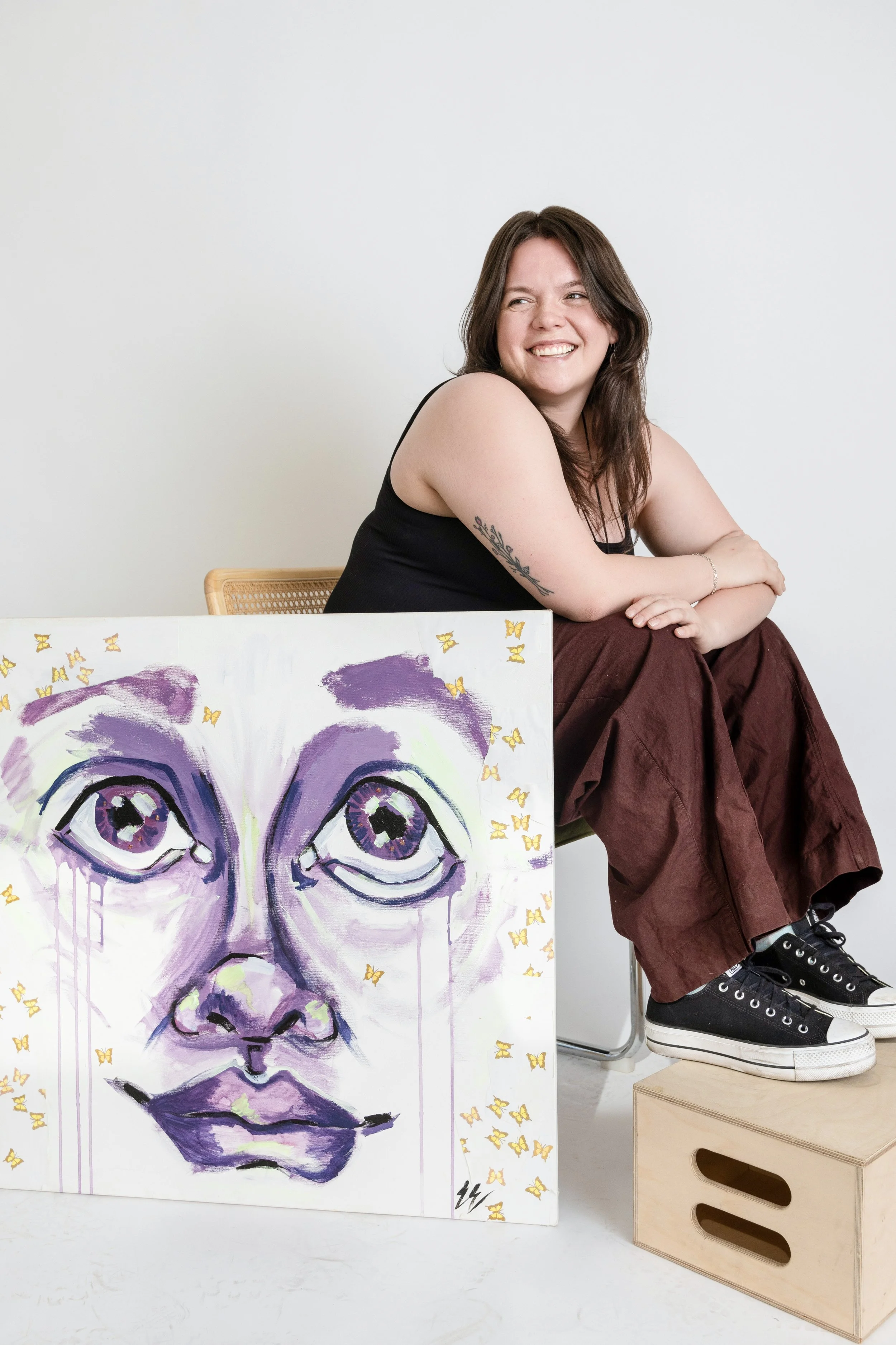 Professional headshot of a woman painter in casual clothing, smiling over her shoulder.