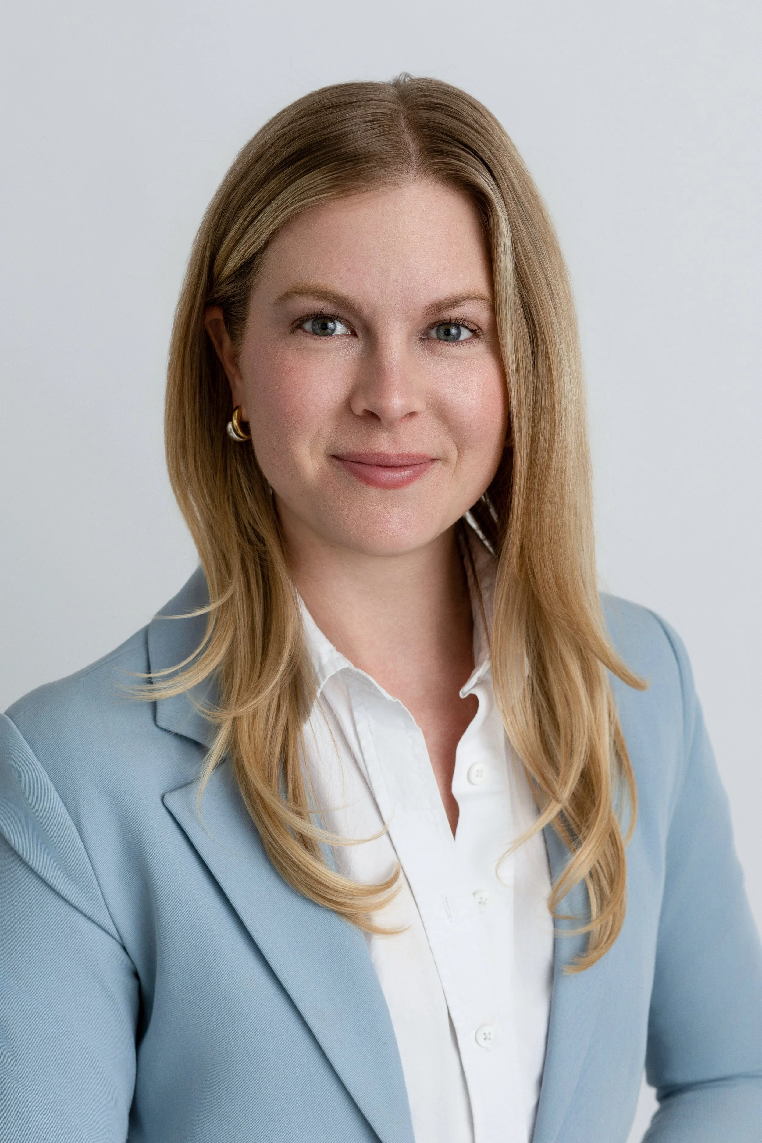 Woman in a blue blazer smiling softly but confid looking at her phone in surprise during a personal branding shoot in Denver.