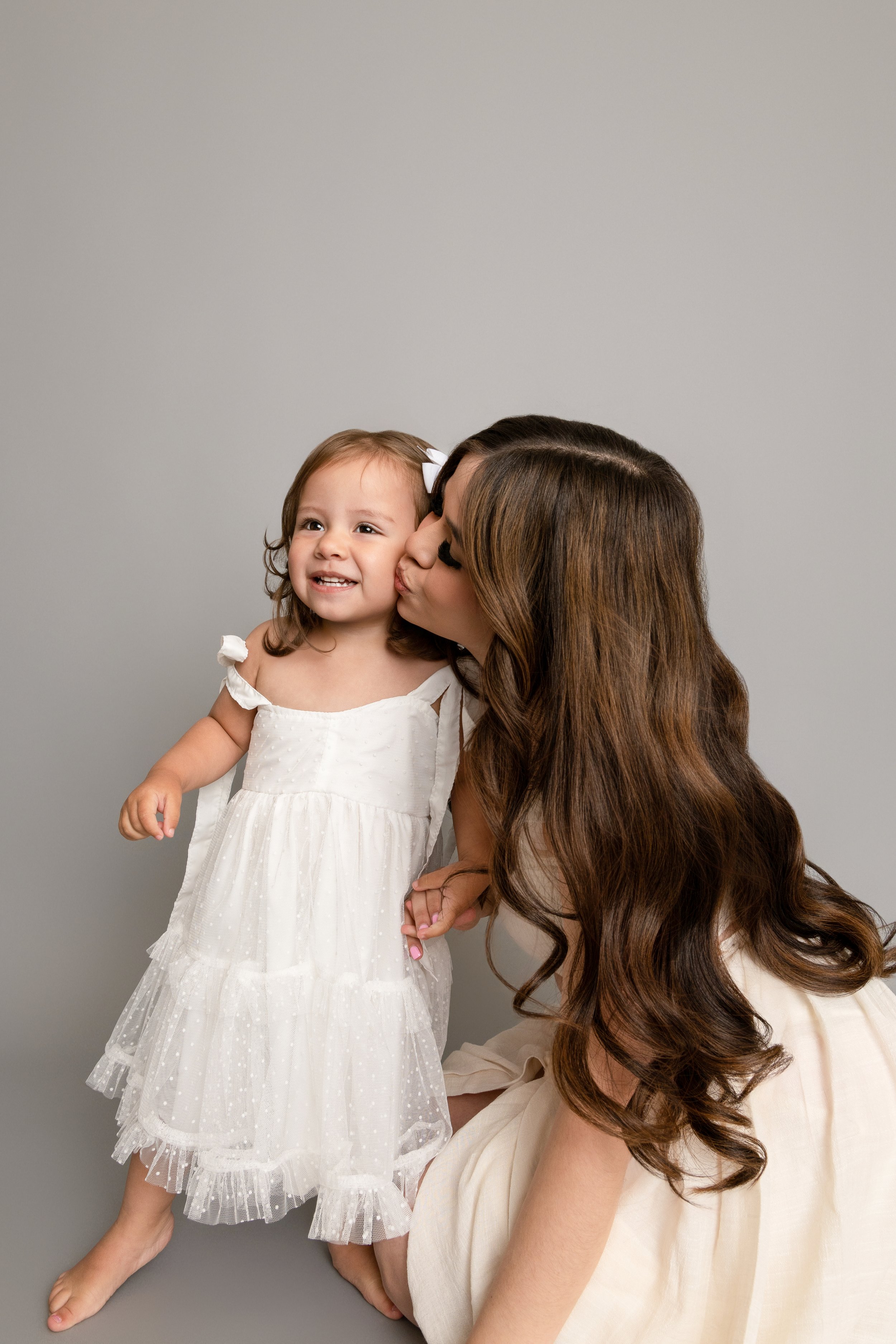 Mother kissing her daughter on the cheek during a second birthday portrait session.