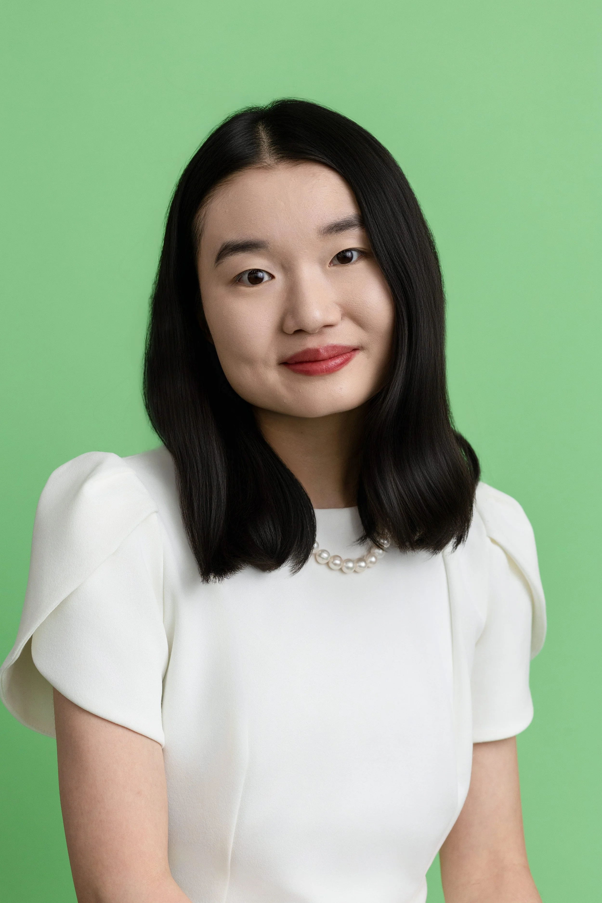 Professional headshot of a woman wearing a white blouse, smiling softly at the camera.