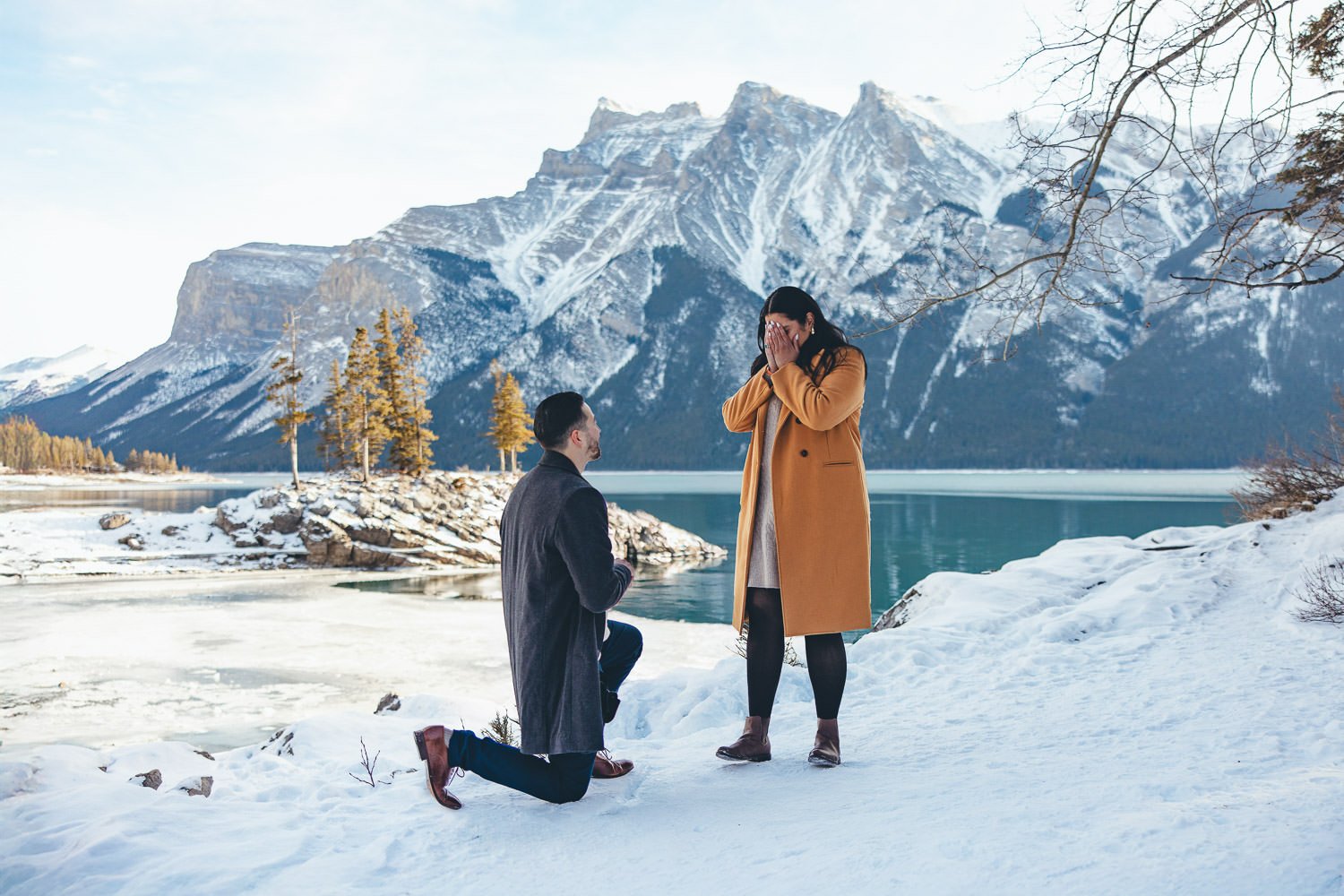 Lake Minnewanka in winter, with a snowy landscape and frozen waters under a pale winter sky.