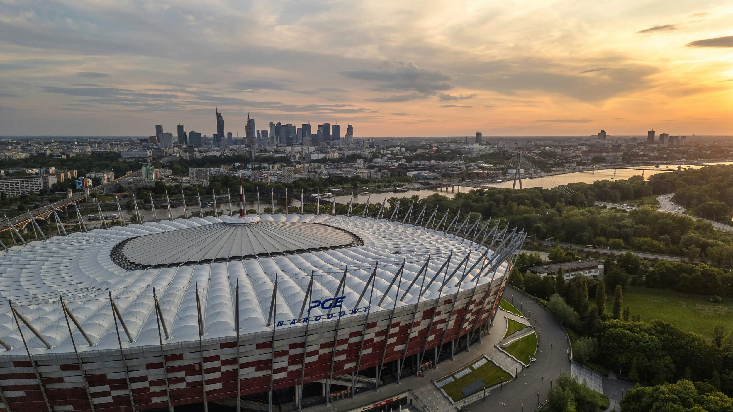 Sunset aerial of a stadium with the city skyline and river behind it