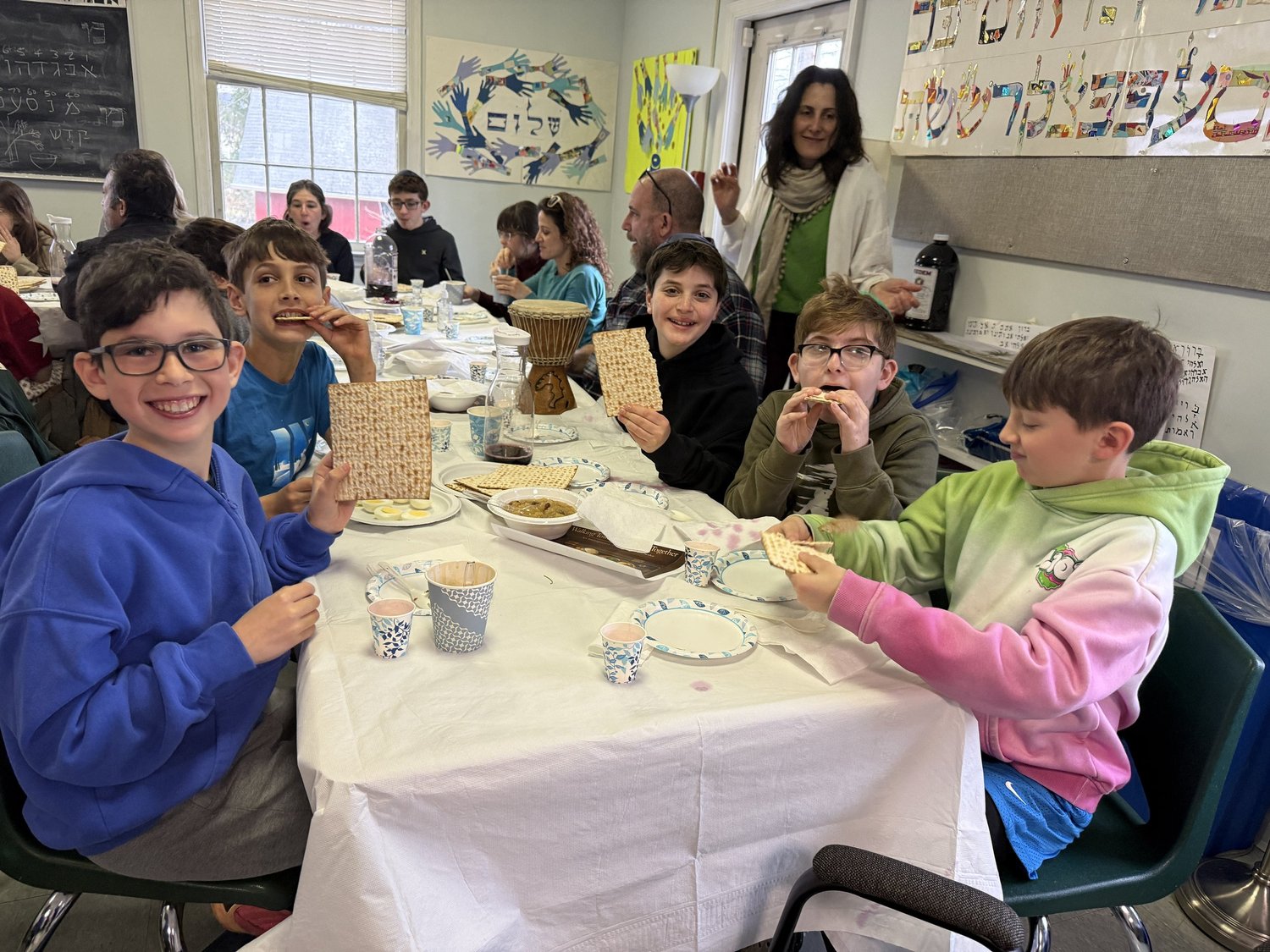 Students holding matzah around a table at a model seder.