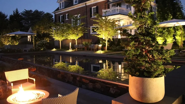 Professionally illuminated pool terrace and garden at a New Jersey home after dark
