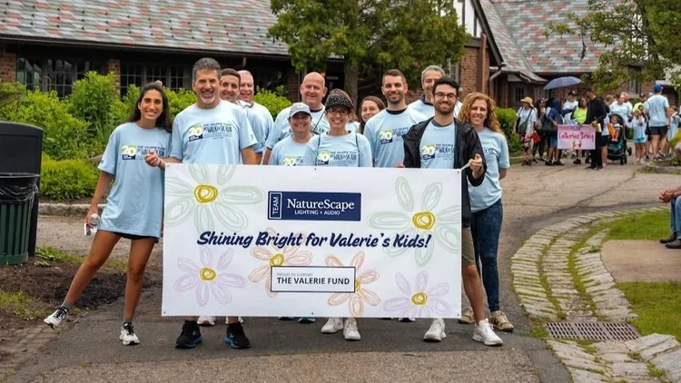 Team NatureScape at the 2026 Valerie Fund Walk holding a Shining Bright for Valerie’s Kids banner