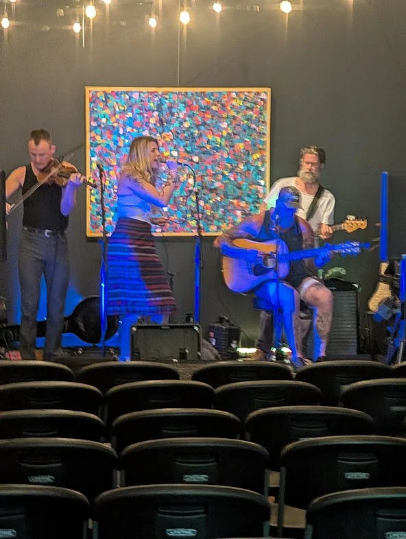 Musicians sharing an acoustic performance on the Black Iris gallery stage