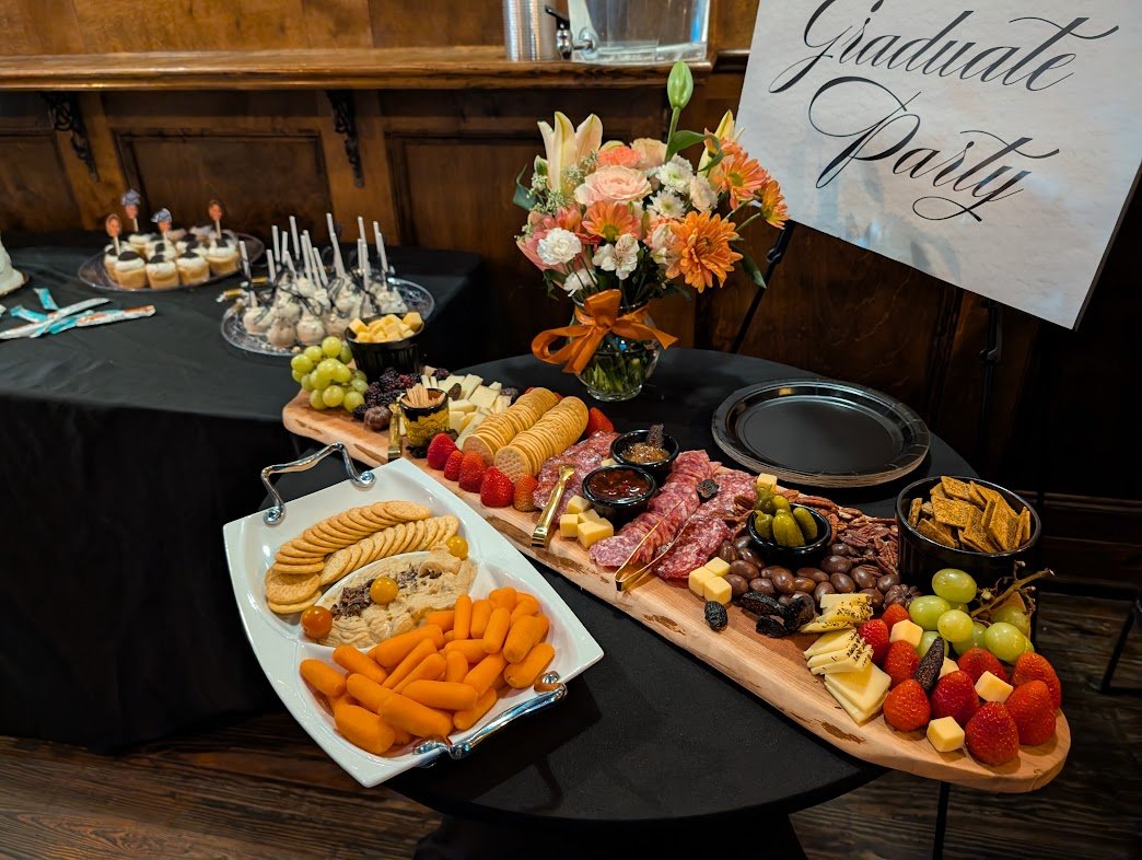 A Black Iris grazing spread with cheeses, fruit, and crackers