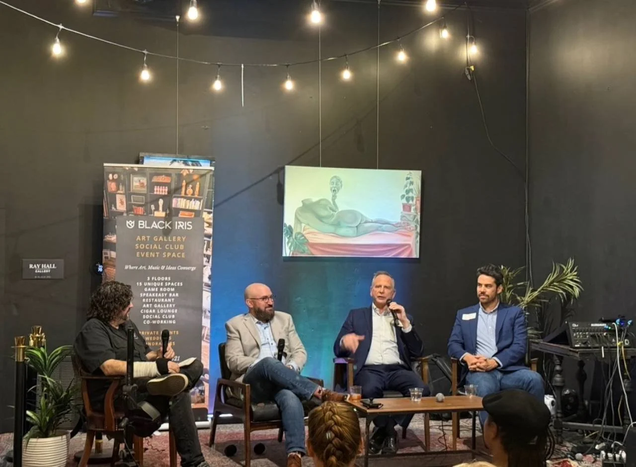A panelist speaks on stage during an event at Black Iris