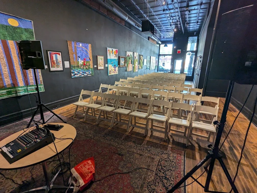 Black Iris art gallery arranged with seated rows and a presentation area