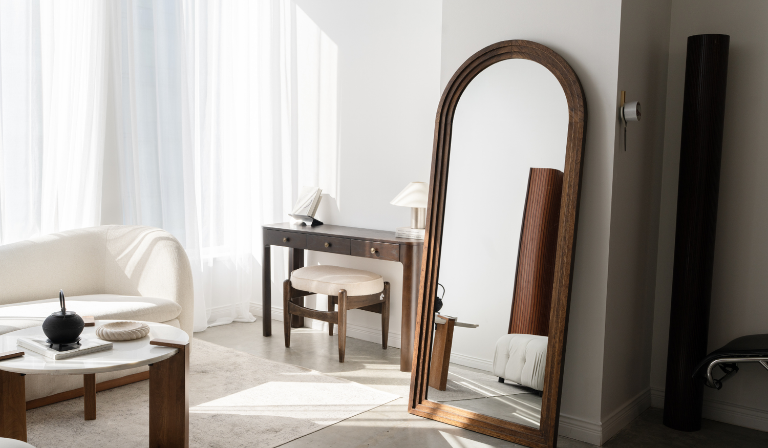 Arched floor mirror reflecting the studio seating area.