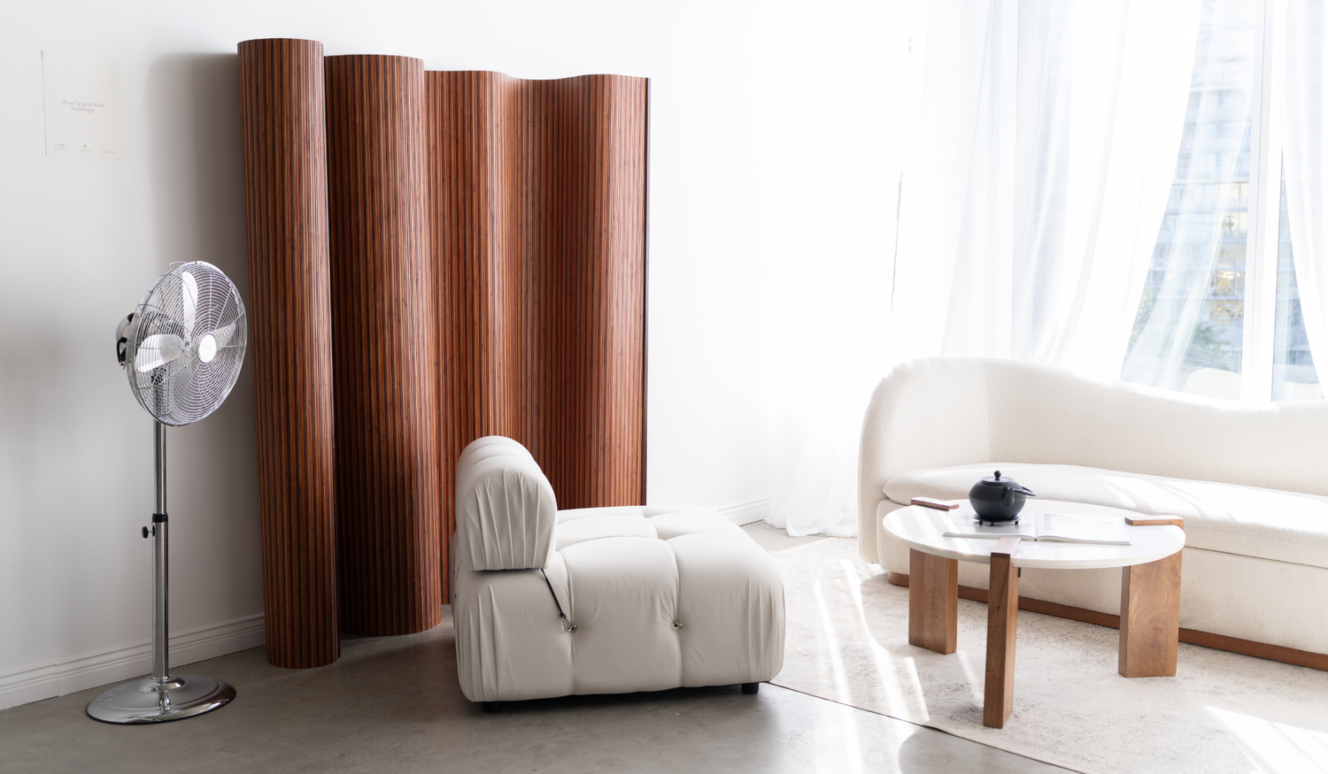Cream lounge chair and curved wood divider beside the window.