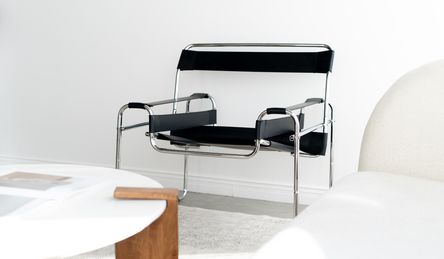 Black and chrome chair beside the cream sofa and coffee table.