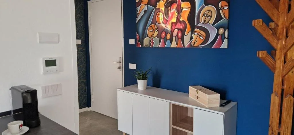 ein Zimmer mit einer blauen Wand und einem Gemälde an der Wand in der Unterkunft Bellavista Apartment Garda in Garda