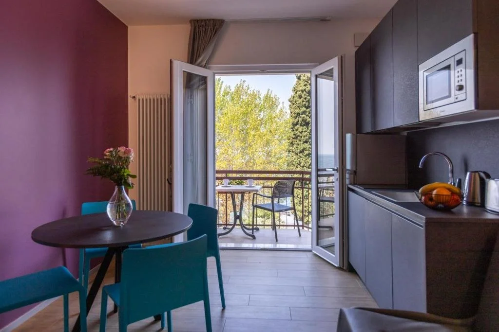 eine Küche und ein Esszimmer mit Tisch und Balkon in der Unterkunft Residence Solei Classic & Plus in Brenzone sul Garda