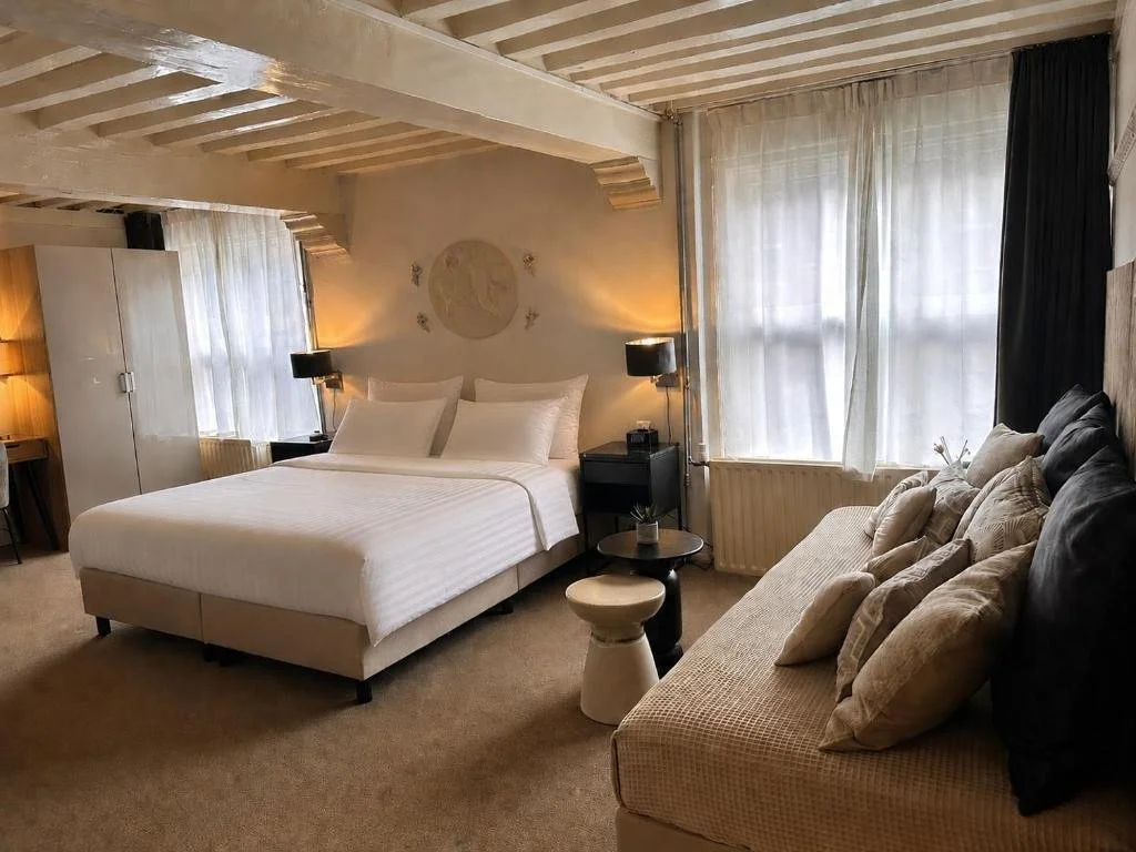 ein Schlafzimmer mit einem großen weißen Bett und einer Couch in der Unterkunft Grand Canal Boutique Hotel Delft in Delft