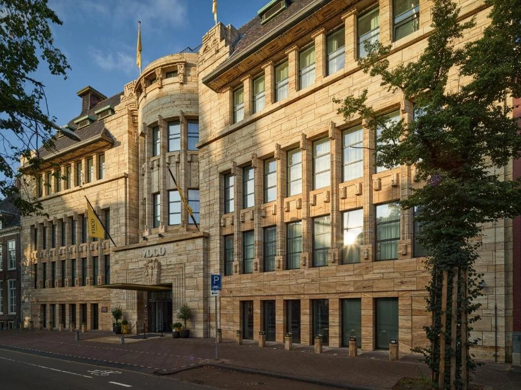 ein großes Backsteingebäude an der Ecke einer Straße in der Unterkunft voco The Hague by IHG in Den Haag