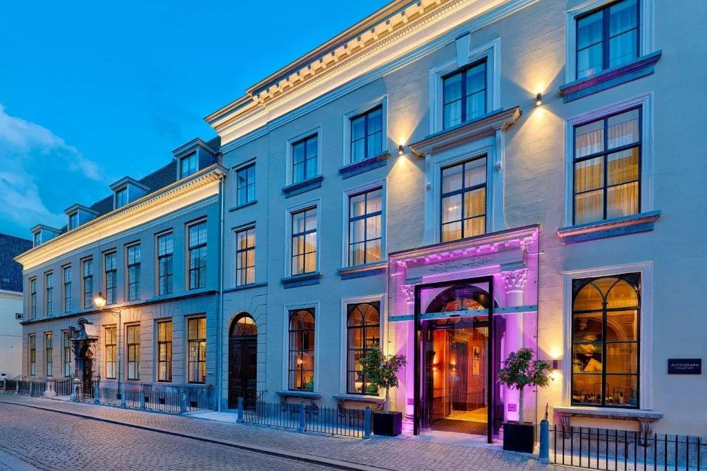 ein großes weißes Gebäude mit einer violetten Fassade in der Unterkunft Hotel Nassau Breda, Autograph Collection in Breda